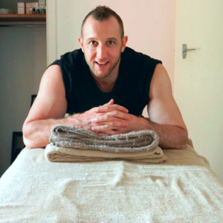 About Us: A man sitting on a massage table with a towel, offering relaxation and wellness services.