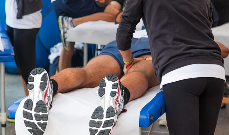 A man receiving a sports massage on a bed with his feet on a table.